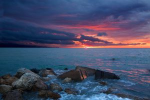 Foto de unas vistas espectaculares el atardecer con el sol escondiéndose entre el mar y las nubes.